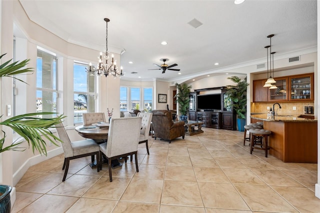 dining area featuring light tile patterned flooring, crown molding, sink, and ceiling fan with notable chandelier