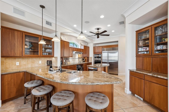 kitchen with appliances with stainless steel finishes, sink, backsplash, kitchen peninsula, and hanging light fixtures