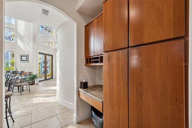 interior space featuring light tile patterned flooring, french doors, and a towering ceiling