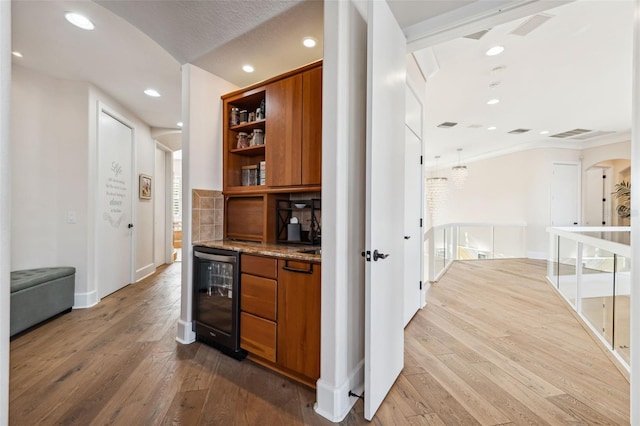 bar with hardwood / wood-style flooring, light stone counters, and beverage cooler