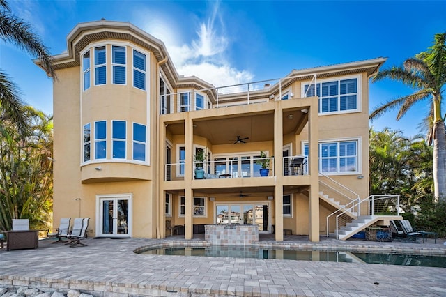 rear view of property with ceiling fan, a patio, french doors, and a balcony