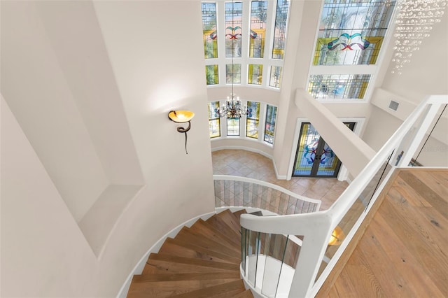 6015 Kipps Colony Dr E, Gulfport, FL 33707 - staircase featuring a chandelier, a high ceiling, and tile patterned flooring