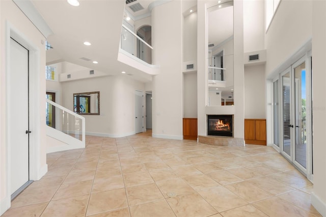 6015 Kipps Colony Dr E, Gulfport, FL 33707 - unfurnished living room featuring a high ceiling, recessed lighting, tile patterned floors, a glass covered fireplace, and stairs