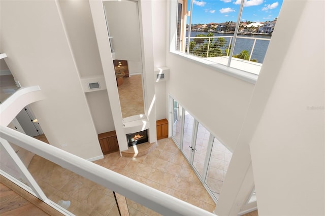 6015 Kipps Colony Dr E, Gulfport, FL 33707 - stairway with a towering ceiling, a water view, a lit fireplace, and tile patterned floors