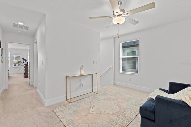 living area with light colored carpet and ceiling fan