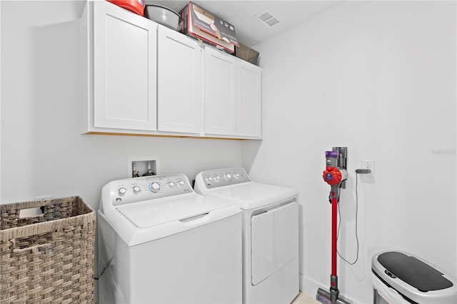 clothes washing area featuring washer and clothes dryer and cabinets