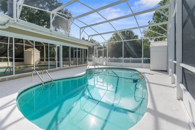 view of swimming pool with glass enclosure, a patio area, and a storage shed