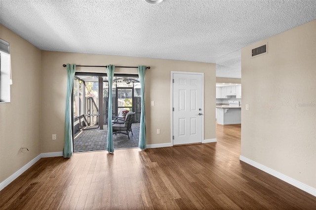 spare room featuring hardwood / wood-style floors and a textured ceiling