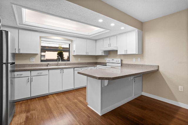 kitchen with white appliances, kitchen peninsula, sink, and white cabinets