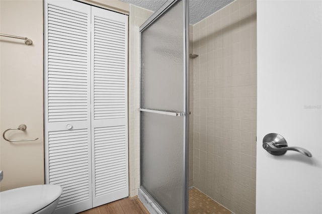 bathroom featuring a shower with shower door, hardwood / wood-style floors, and toilet