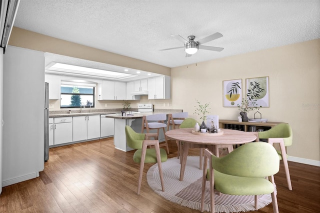 dining room with ceiling fan, wood-type flooring, sink, and a textured ceiling