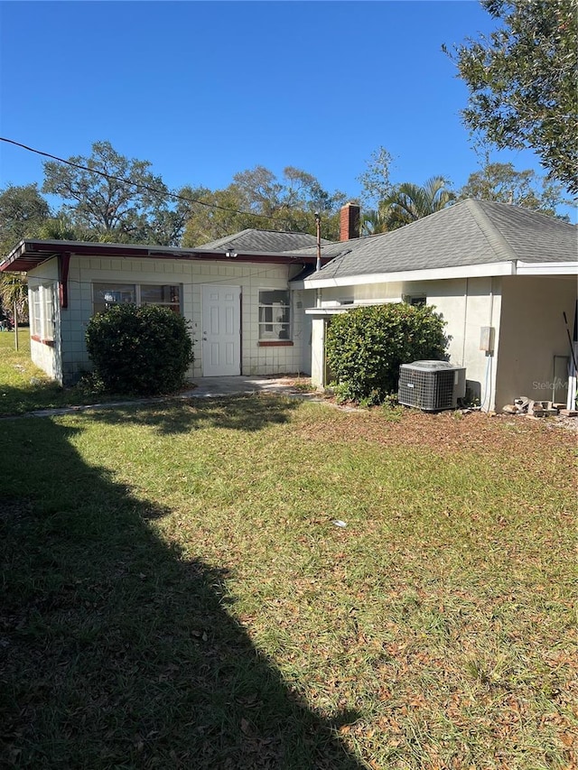 rear view of house featuring a yard and central AC