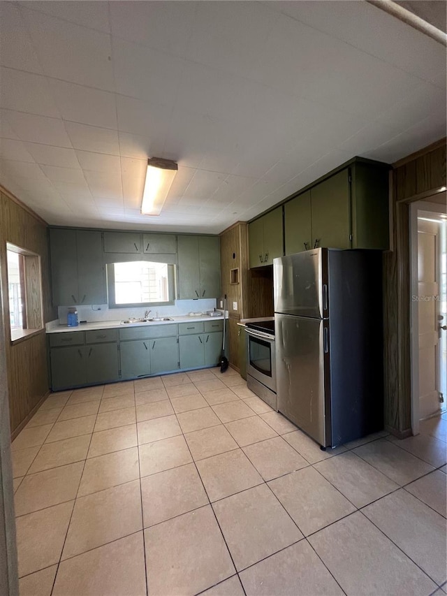 kitchen featuring wood walls, sink, light tile patterned floors, and stainless steel appliances