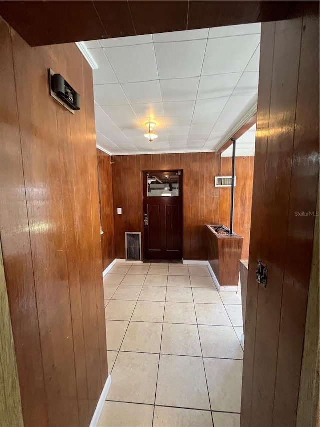 entryway with wood walls, light tile patterned floors, and ornamental molding