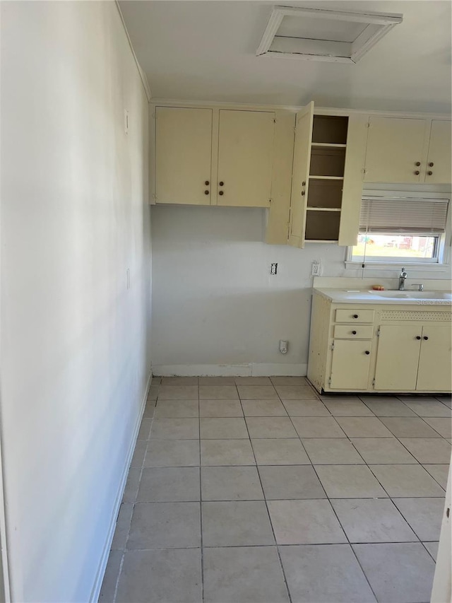 kitchen with cream cabinetry, light tile patterned flooring, and sink