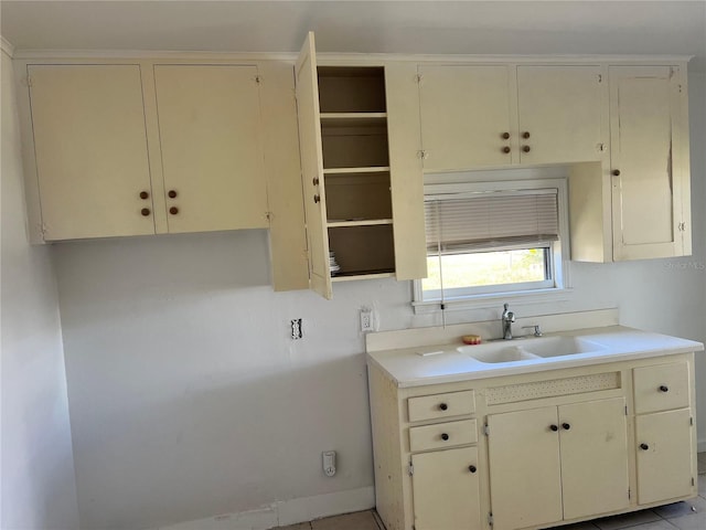 kitchen with sink, light tile patterned floors, and cream cabinetry