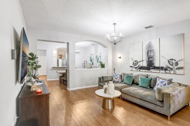 living room featuring a chandelier, wood-type flooring, and a textured ceiling