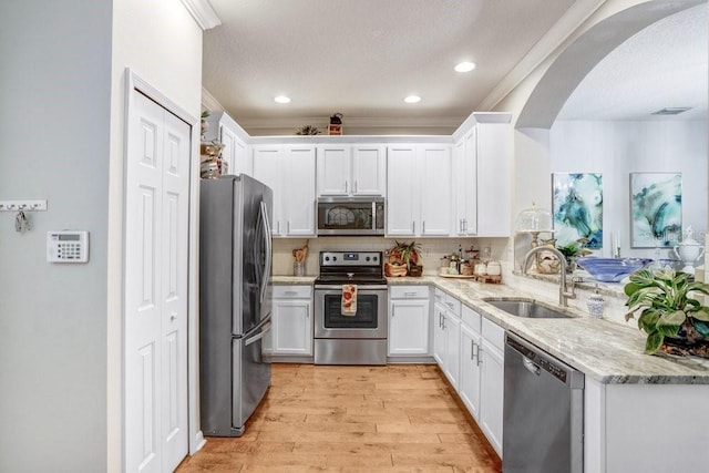 kitchen featuring sink, decorative backsplash, appliances with stainless steel finishes, light stone counters, and white cabinetry