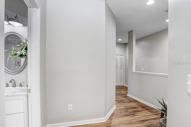 hallway with hardwood / wood-style floors, sink, and a textured ceiling