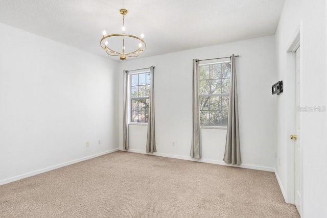 empty room with baseboards, carpet floors, and an inviting chandelier