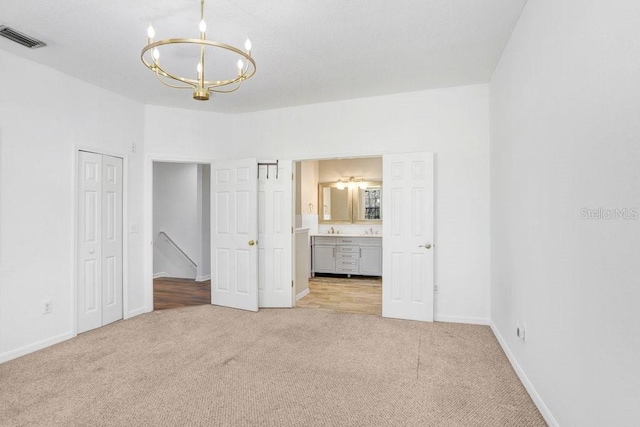 unfurnished bedroom featuring visible vents, light carpet, ensuite bath, a chandelier, and baseboards