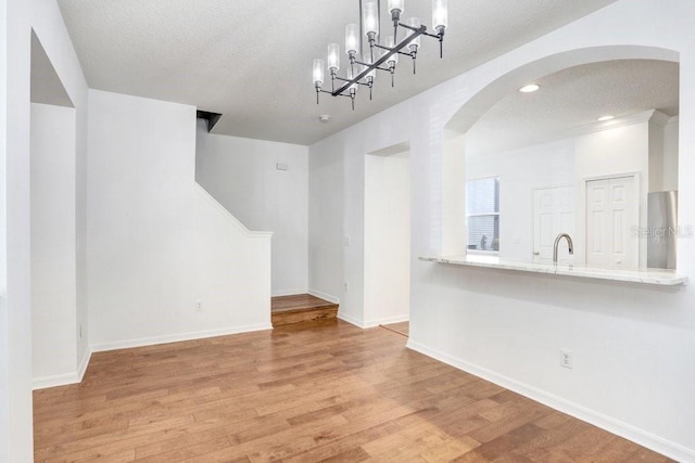 interior space featuring a sink, a textured ceiling, baseboards, and wood finished floors