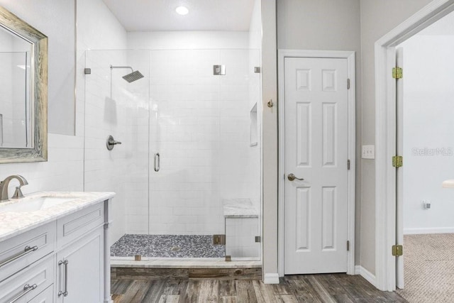 full bath featuring a stall shower, baseboards, wood finished floors, and vanity