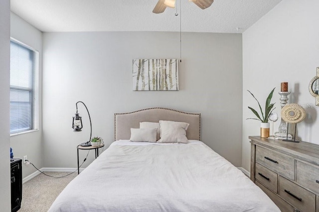 carpeted bedroom with ceiling fan, a textured ceiling, and baseboards