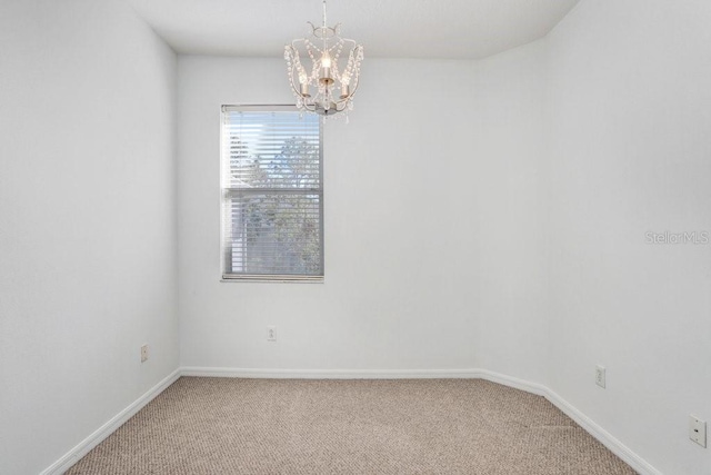 unfurnished room featuring light carpet, a notable chandelier, and baseboards