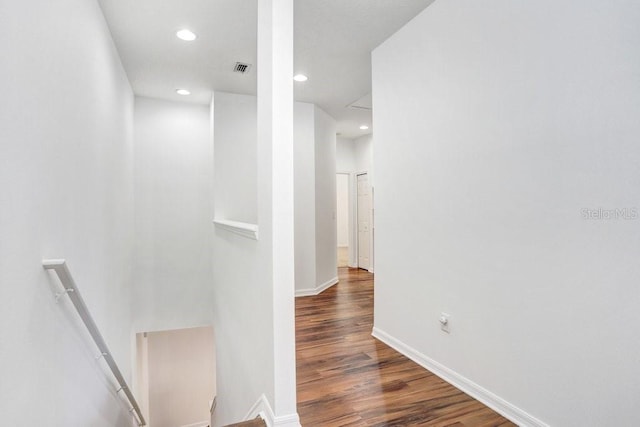 hallway with recessed lighting, wood finished floors, visible vents, an upstairs landing, and baseboards