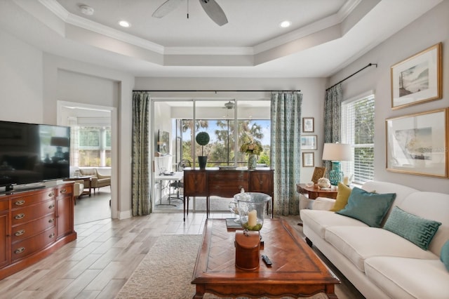 living room featuring ceiling fan, a wealth of natural light, crown molding, and a raised ceiling