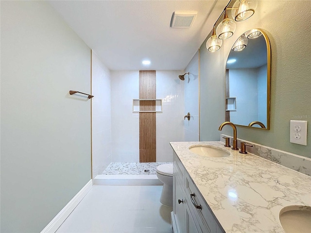 bathroom featuring a tile shower, vanity, and toilet