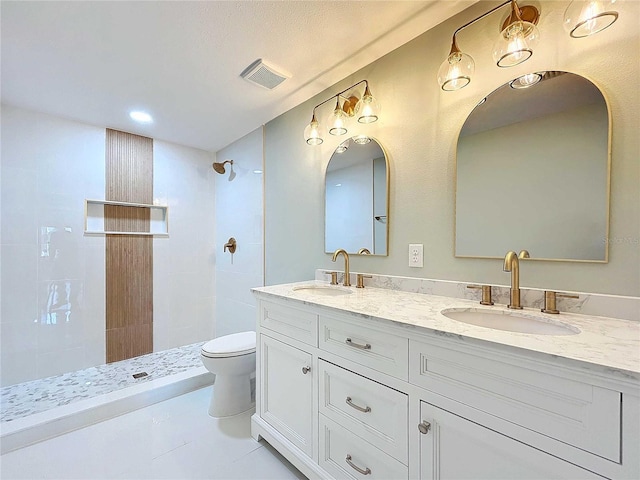 bathroom with tiled shower, tile patterned floors, vanity, and toilet