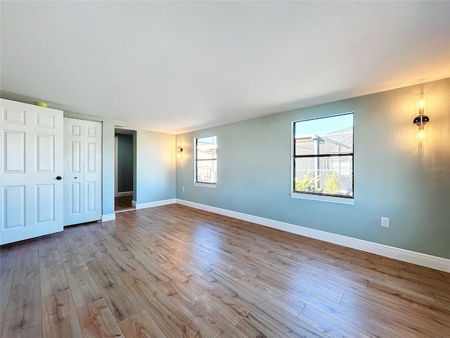 unfurnished bedroom featuring multiple windows, a closet, and light wood-type flooring