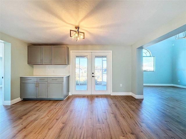 interior space featuring gray cabinets, light hardwood / wood-style floors, backsplash, and french doors