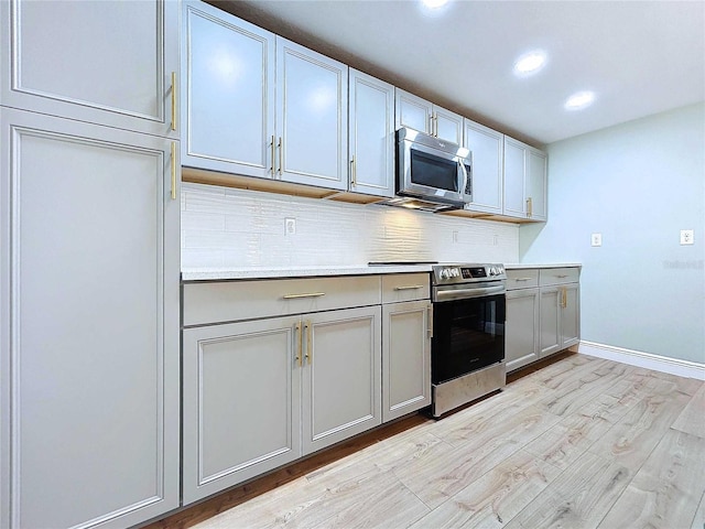 kitchen with gray cabinets, decorative backsplash, light hardwood / wood-style flooring, and appliances with stainless steel finishes