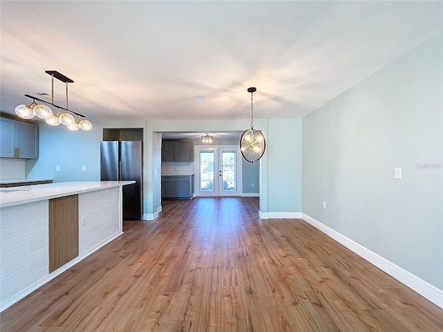 kitchen featuring french doors, light hardwood / wood-style floors, stainless steel refrigerator, and hanging light fixtures