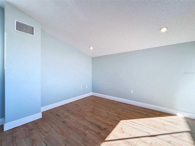 empty room featuring a textured ceiling and hardwood / wood-style flooring