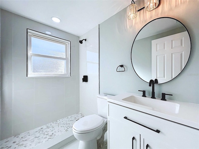 bathroom featuring tiled shower, vanity, and toilet