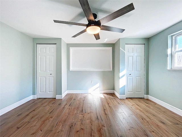 unfurnished bedroom with ceiling fan, light hardwood / wood-style flooring, and multiple closets