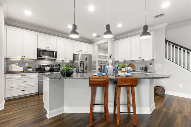 kitchen featuring decorative light fixtures, dark stone counters, white cabinets, and appliances with stainless steel finishes