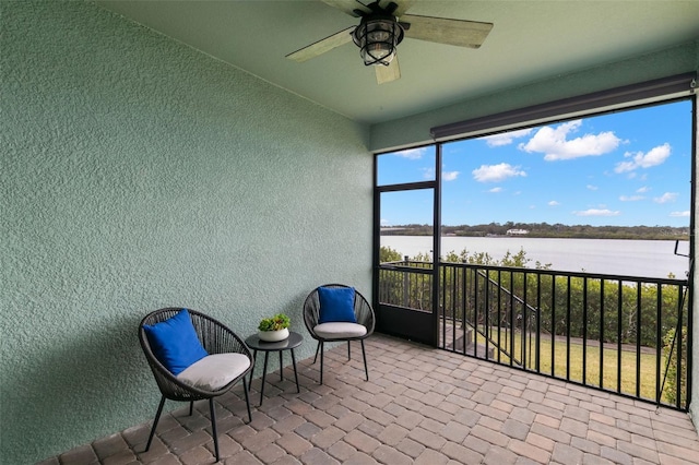 sunroom / solarium with a water view and ceiling fan