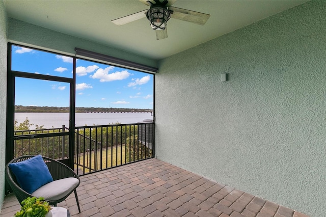 unfurnished sunroom featuring ceiling fan and a water view