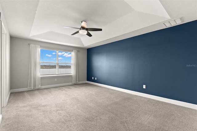 carpeted empty room with a textured ceiling, a raised ceiling, and ceiling fan