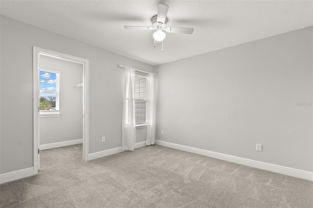 empty room with light carpet, a wealth of natural light, and ceiling fan