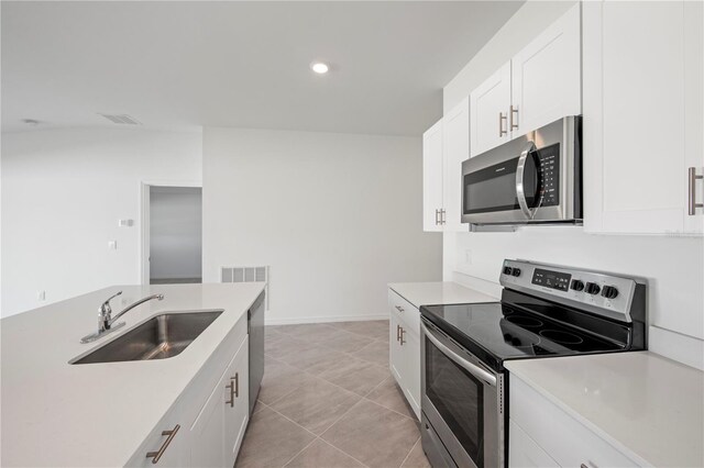 kitchen featuring white cabinets, sink, light tile patterned floors, and stainless steel appliances