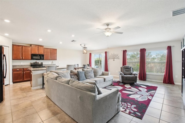 living room featuring light tile patterned floors, a textured ceiling, a healthy amount of sunlight, and ceiling fan