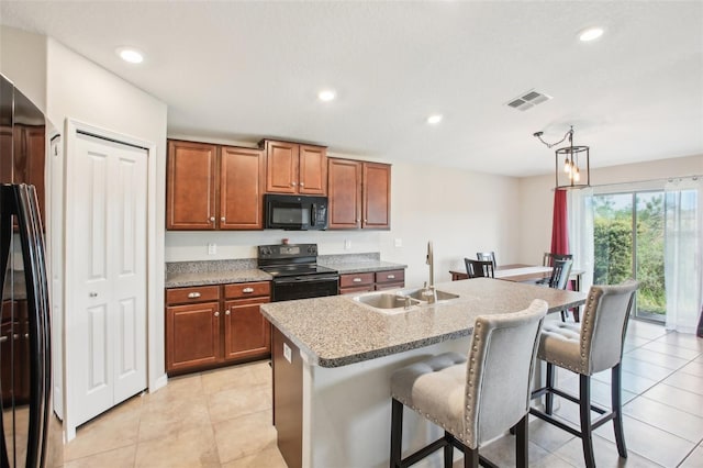 kitchen with sink, a kitchen breakfast bar, black appliances, a center island with sink, and decorative light fixtures