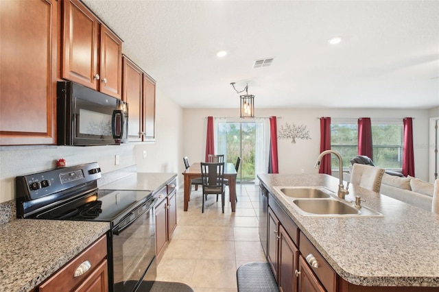 kitchen with light tile patterned flooring, sink, an island with sink, and black appliances