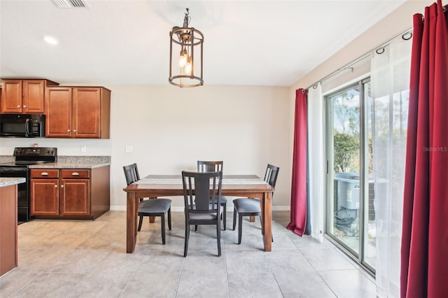 kitchen with light stone countertops, light tile patterned floors, hanging light fixtures, and black appliances